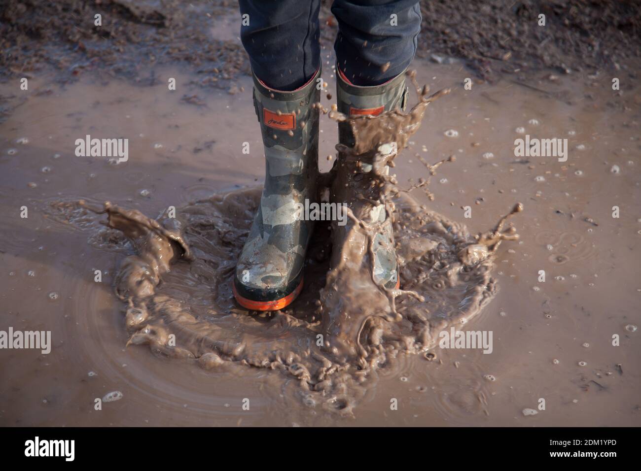 Niño saltando en un charco de lodo fotografías e imágenes de alta