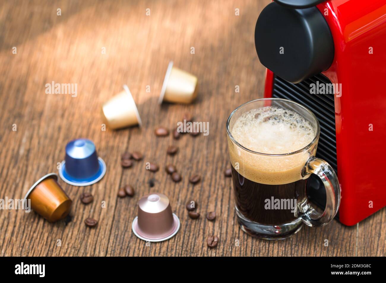 Cafetera Espresso con cápsulas de hacer café negro en un vaso sobre la mesa  de madera y amanecer natural Fotografía de stock - Alamy