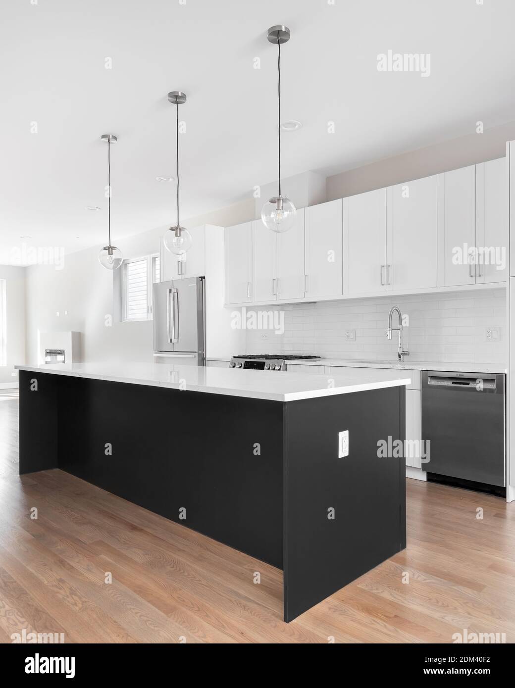 Una moderna cocina blanca con una isla negra, electrodomésticos de acero  inoxidable, encimeras de granito blanco y un grifo cromado Fotografía de  stock - Alamy