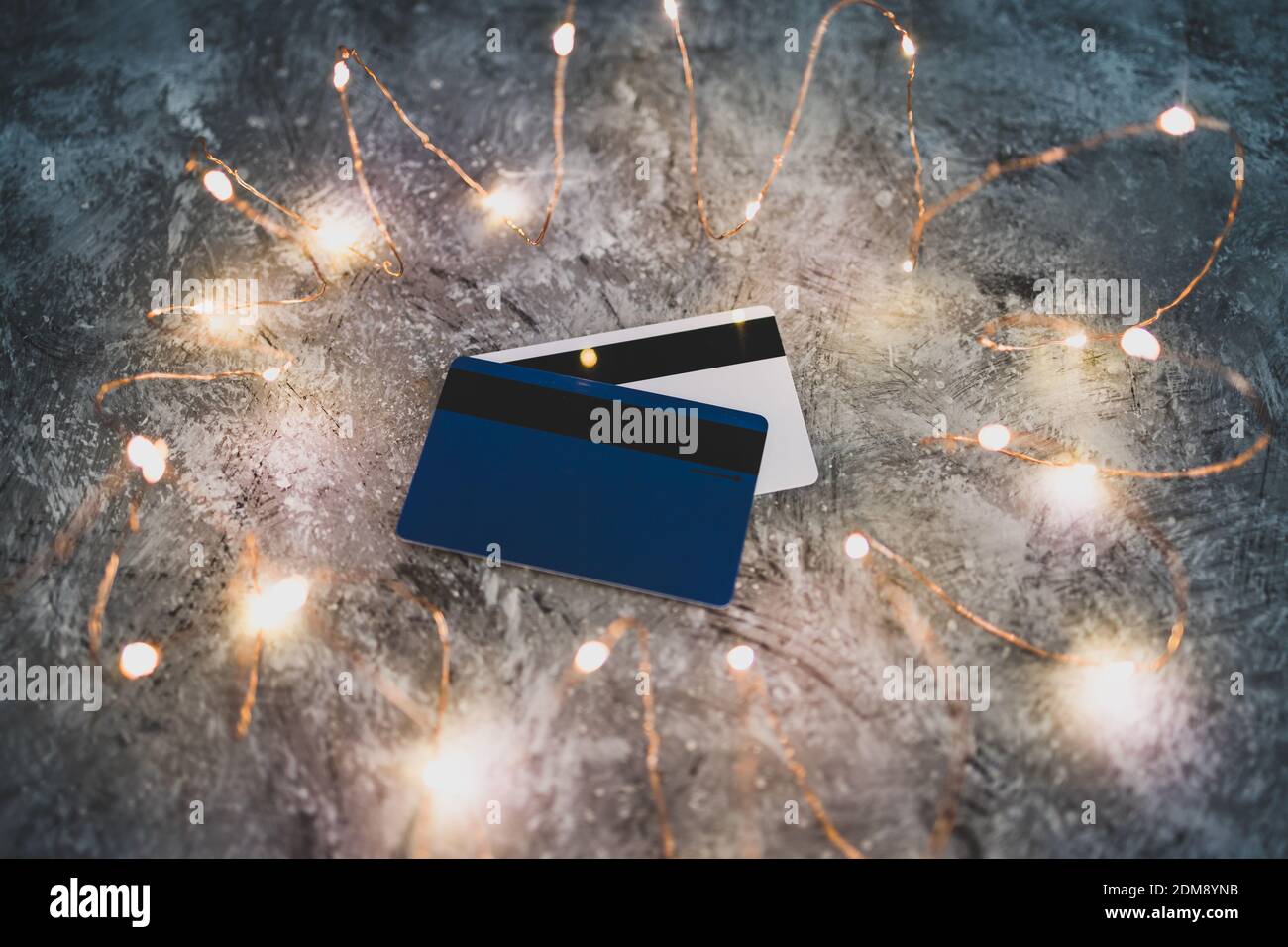 compras y consumismo imagen conceptual, tarjetas de crédito en un escritorio de concreto rodeado de brillantes luces de hadas Foto de stock