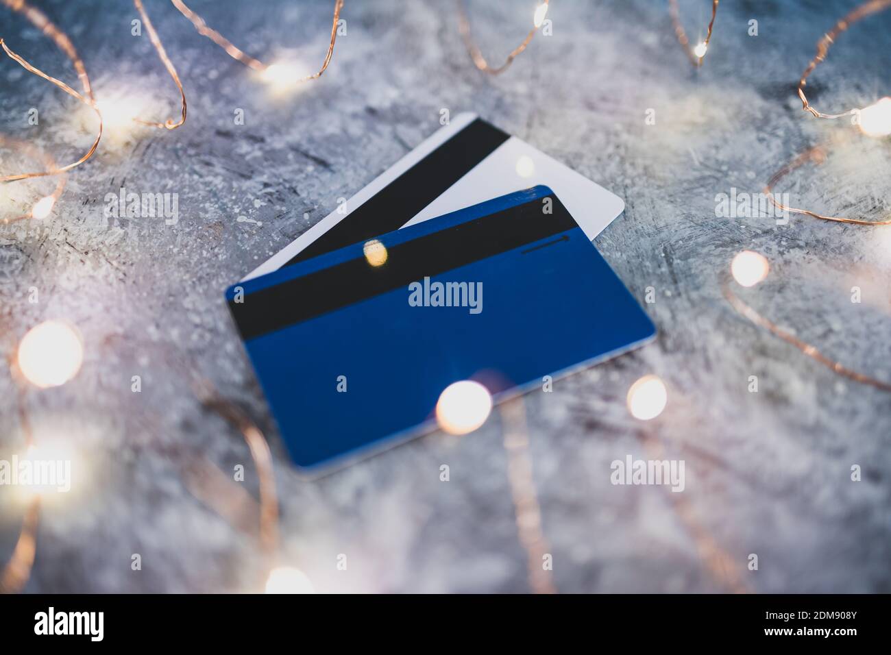 compras y consumismo imagen conceptual, tarjetas de crédito en un escritorio de concreto rodeado de brillantes luces de hadas Foto de stock