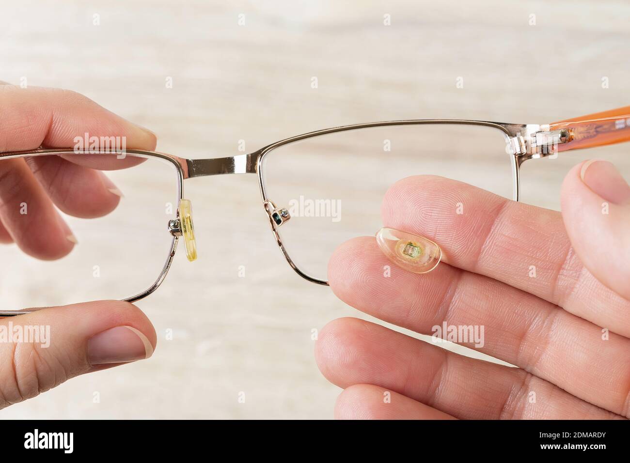 Las manos sostienen los anteojos y la almohadilla de la nariz los rompió  contra el escritorio marrón. Gafas con cables de ojos dañados. Rotura de  las gafas de corrección de la visión