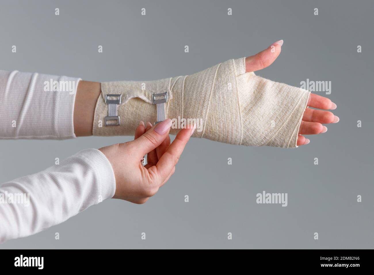 Primer plano de la mujer envolviendo su muñeca dolorosa con un vendaje  ortopédico flexible y elástico después de deportes o lesiones infructuosas.  Síndrome del túnel carpiano, artritis, concepto de esguince del brazo