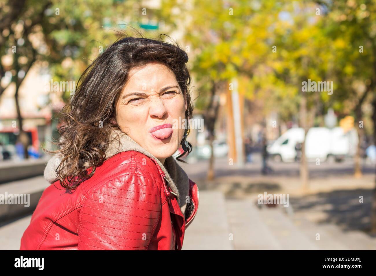 Bonita mujer morena con chaqueta de cuero rojo pegando la lengua Fotografía  de stock - Alamy