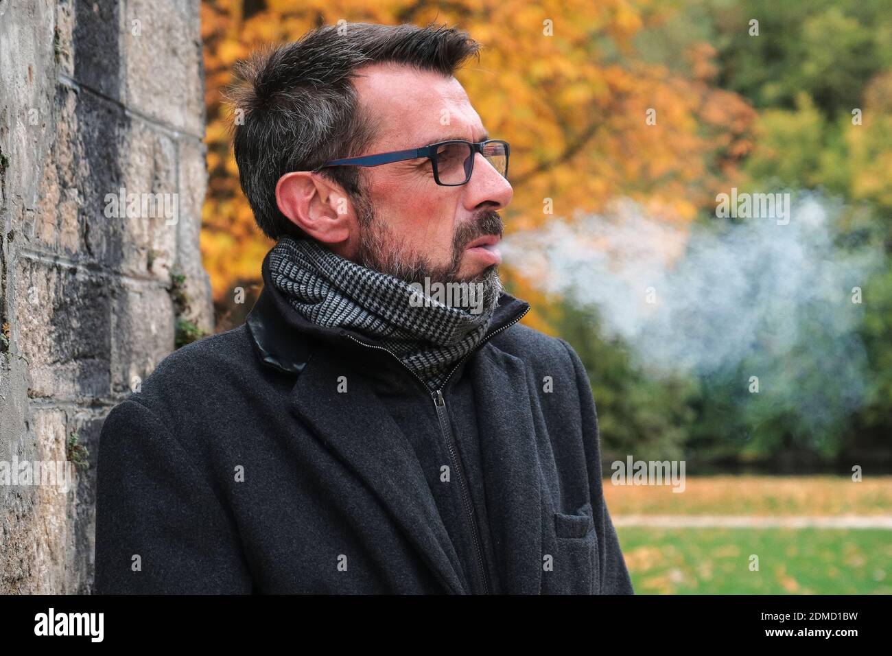 Hombre maduro Fumando Cigarrillo de pie contra los árboles Foto de stock