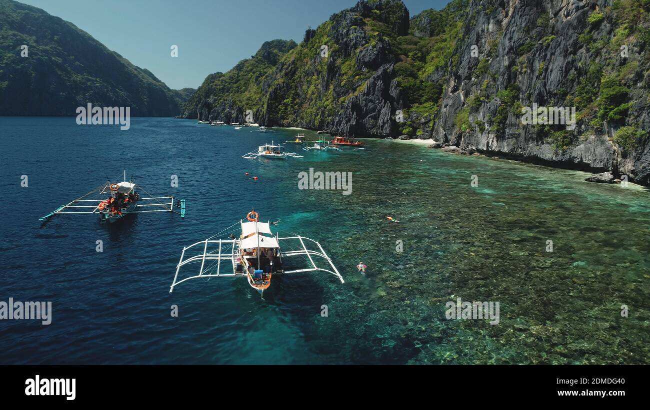 Vacaciones de verano de primer plano en barcos de pasajeros en el océano. Increíble paisaje de la orilla del acantilado con árboles tropicales verdes de la selva. Paisaje marino tropical épico en la isla de montaña de Palawan, Filipinas, Asia Foto de stock