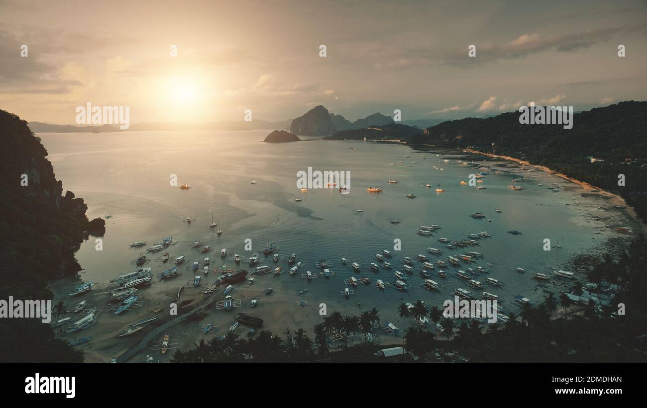 Muelle del océano en la luz del sol aérea: Barcos, barcos, yates en el complejo paraíso tropical. Filipinas hito para las vacaciones en la isla Palawan. Majestuoso paisaje exótico con palmeras y edificio en la playa Foto de stock