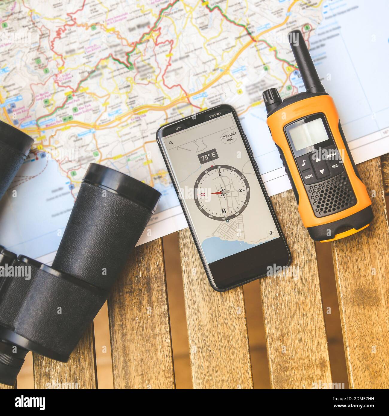 Vista de la vida desde arriba de objetos aventureros. Walkie talkie,  binoculares y brújula electrónica en el smartphone sobre un mapa, listo  para planificar una nueva ruta de viaje. Viaje, concepto de