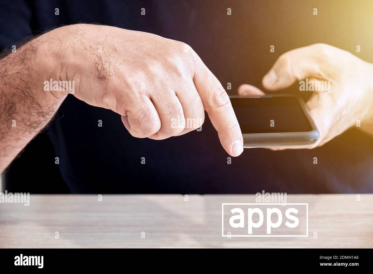 Hombre sostiene un teléfono móvil o smartphone en la mano con el dedo apuntando hacia la palabra apps. Para descargar o utilizar aplicaciones en SMART Foto de stock