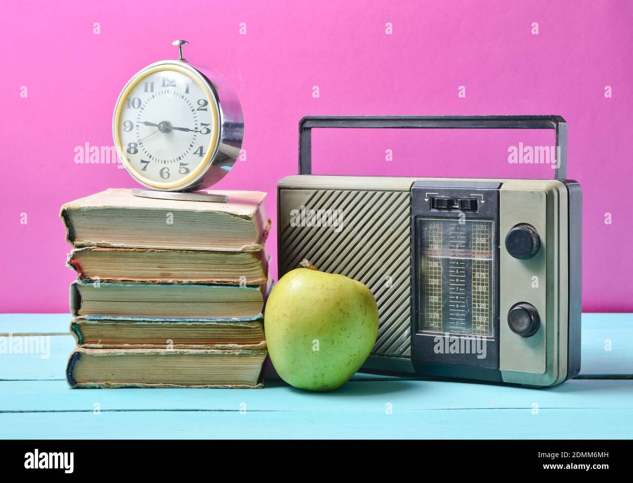 Despertador en la pila de libros viejos, receptor de radio, manzana sobre  fondo rosa. La vida fija retro Fotografía de stock - Alamy