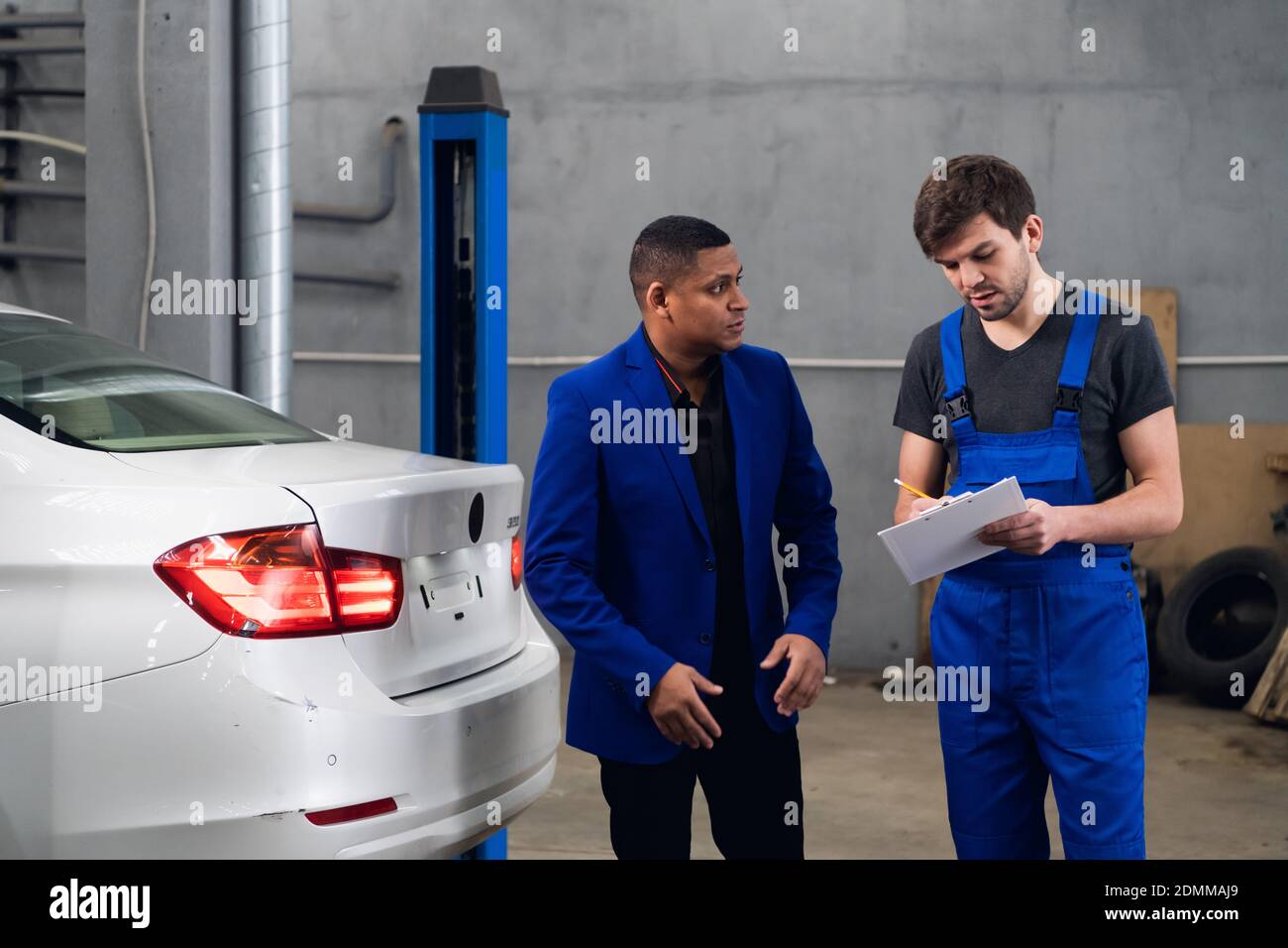 Un cliente que habla con un reparador de un concesionario de coches sobre un reparar Foto de stock