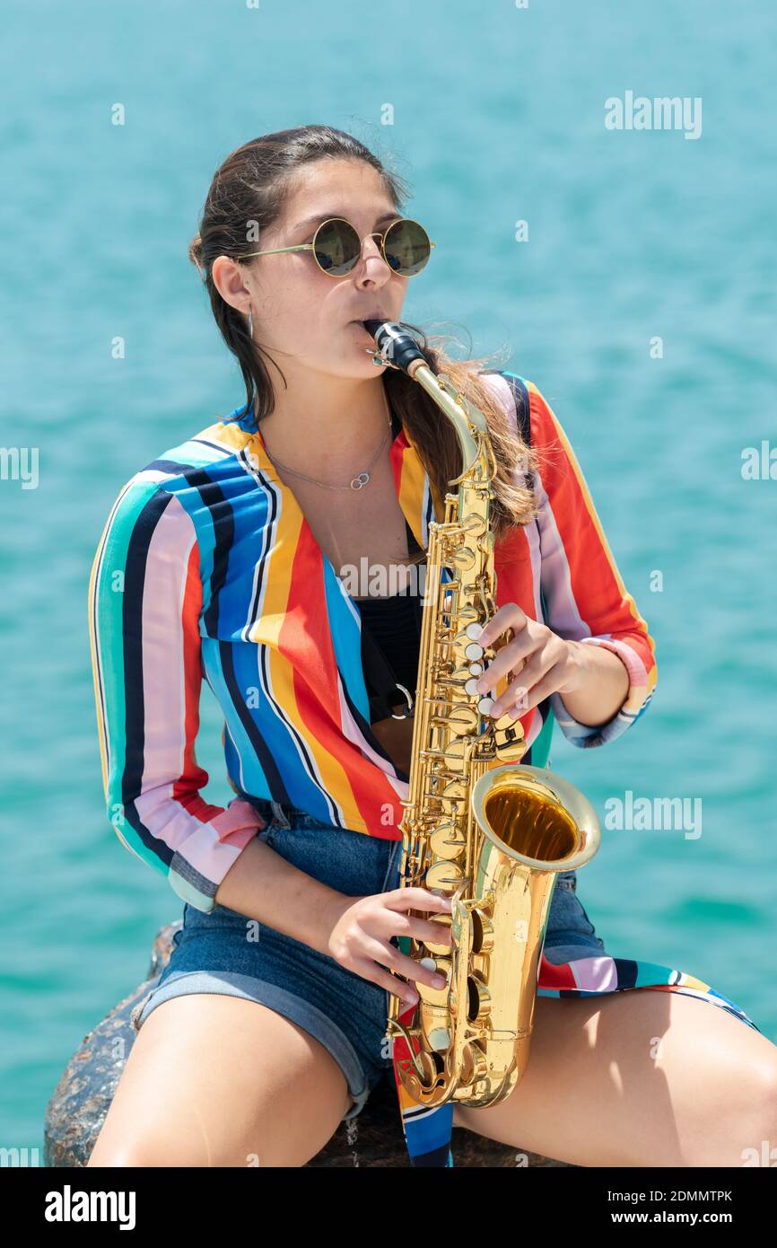 Mujer joven jugando con Saxofón contra el Mar Fotografía de stock - Alamy