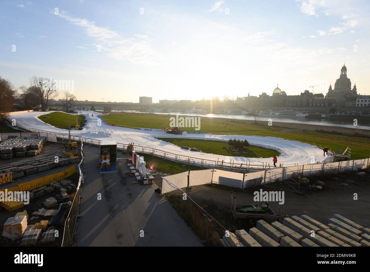 Dresde, Alemania. 17 de diciembre de 2020. Un Pistenbully prepara un futuro curso de competición con nieve artificial en las orillas del Elba contra el telón de fondo de la Ciudad Vieja. A pesar del bloqueo en el Estado libre, las competiciones de sprint de la Copa Mundial de esquí de fondo se celebrarán en Königsufer los días 19 y 20 de diciembre de 2020. Crédito: Sebastian Kahnert/dpa-Zentralbild/dpa/Alamy Live News Foto de stock