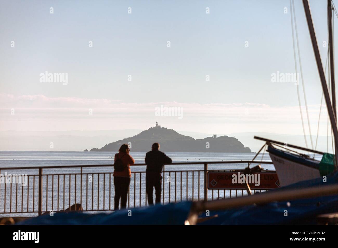 Dos personas de pie en Kinghorn Harbor mirando hacia Inchkeith Island, Fife, Escocia. Foto de stock
