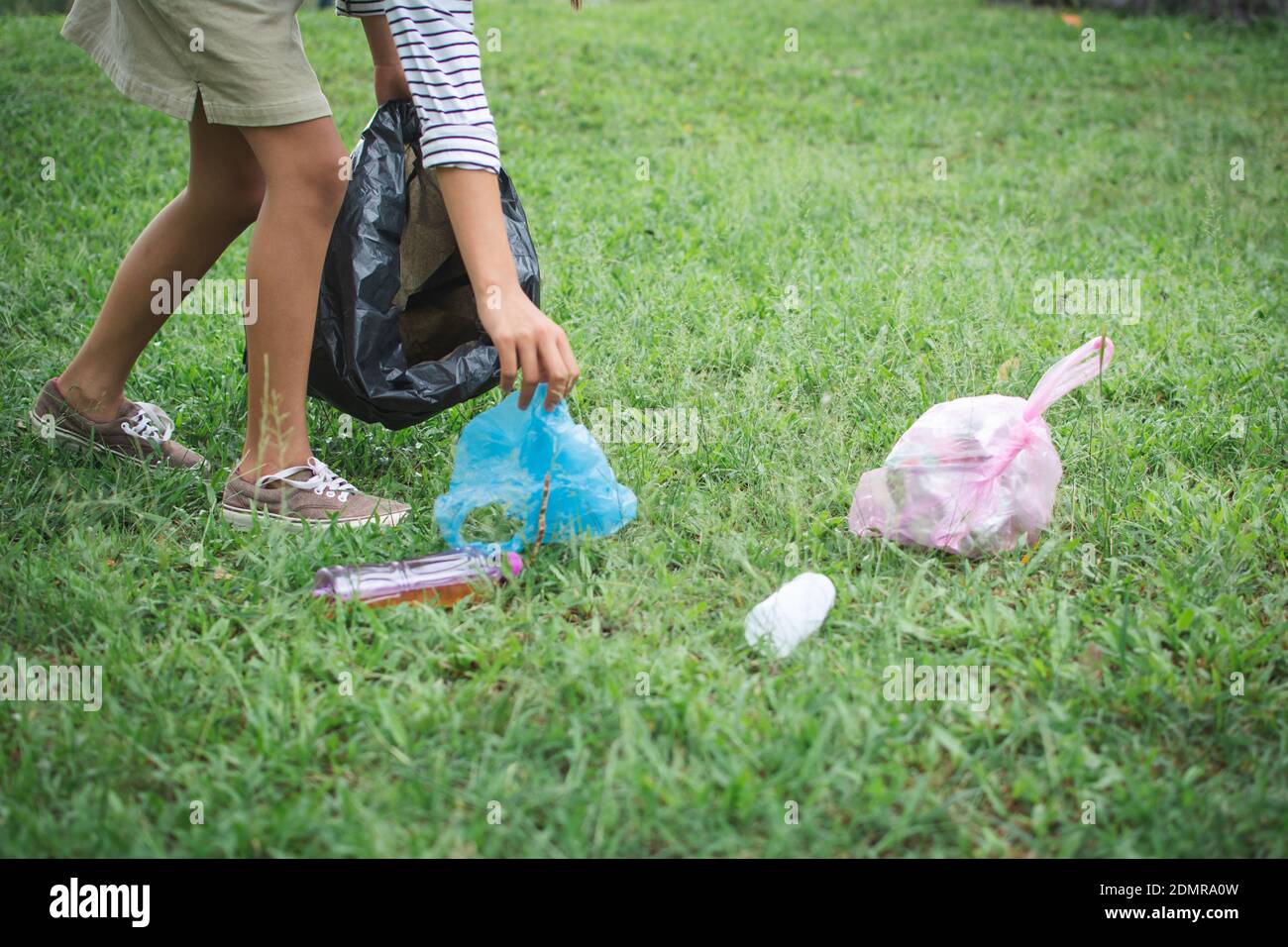 Primer plano de la mujer recolectando basura en el campo de hierba Foto de stock