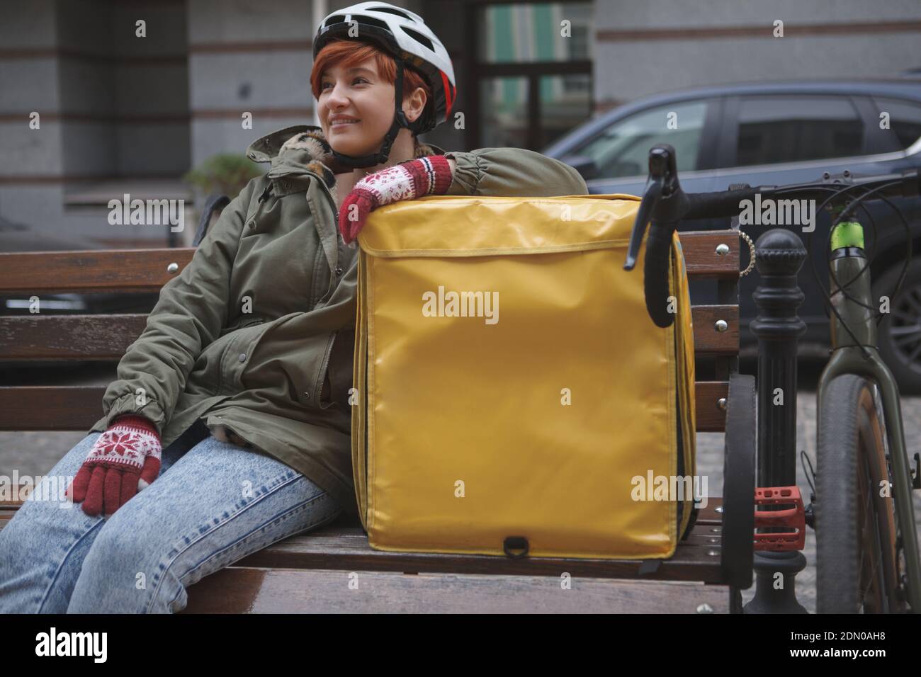 Joven mujer feliz mensajero con casco de bicicleta, descansando después de  andar en bicicleta por las calles de la ciudad con su mochila de entrega  Fotografía de stock - Alamy