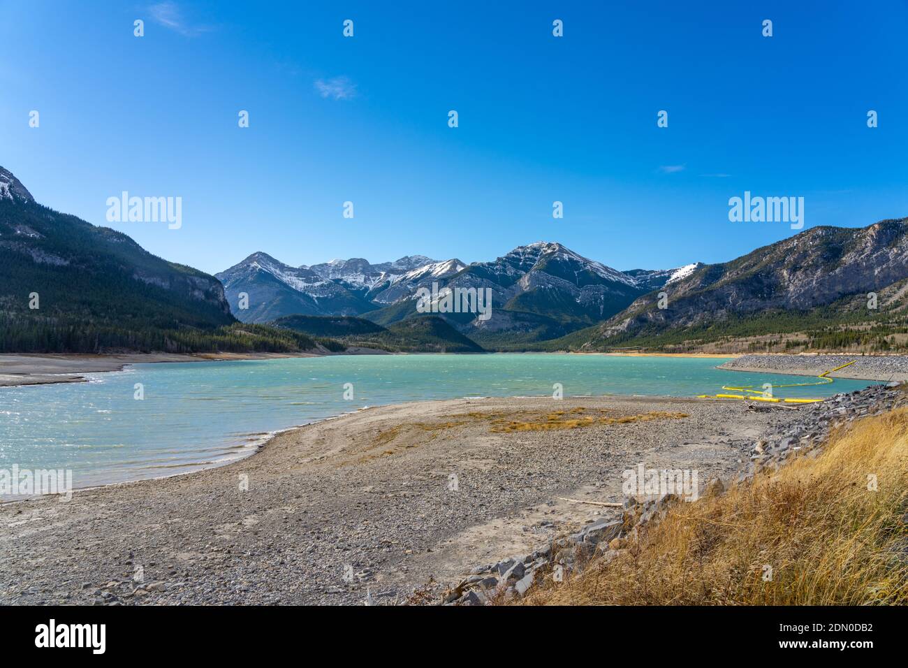 Barrera Lake Dam a orillas del lago en la temporada de otoño soleado día por la mañana. Montañas cubiertas de nieve en el fondo con el cielo azul. kananaskis, Alberta, Canadá. Foto de stock