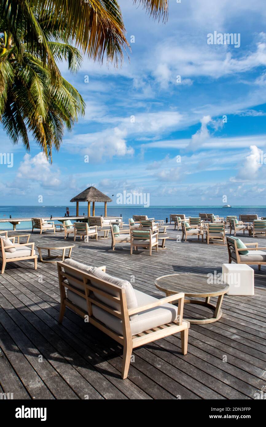 Plataforma de madera con vistas al océano con mesas y sofás, restaurante en un complejo de lujo, paraíso tropical, Maldivas. Foto de stock