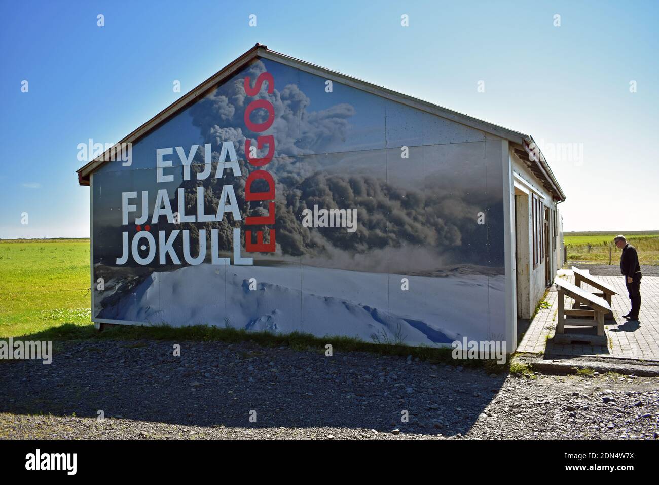 Un pequeño museo familiar dedicado a la erupción del volcán Eyjafjallajokull en 2010. Un hombre lee un signo interpretativo fuera del edificio. Foto de stock