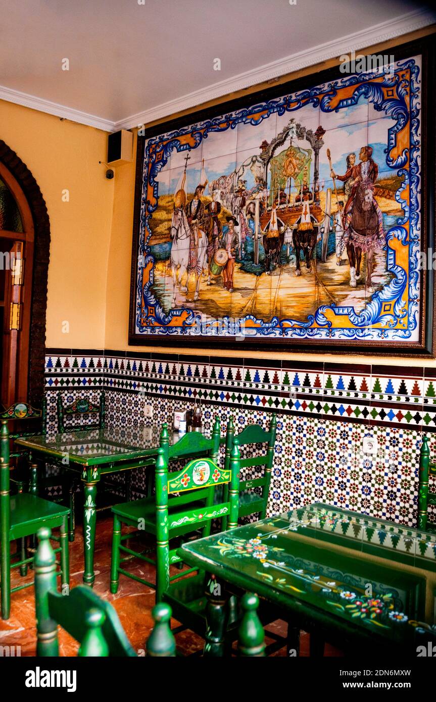 Los revestimientos de azulejos moriscos, un mural de baldosas y sillas y  mesas pintadas a mano reflejan un colorido patrimonio artístico en Sevilla,  al sur de España Fotografía de stock - Alamy