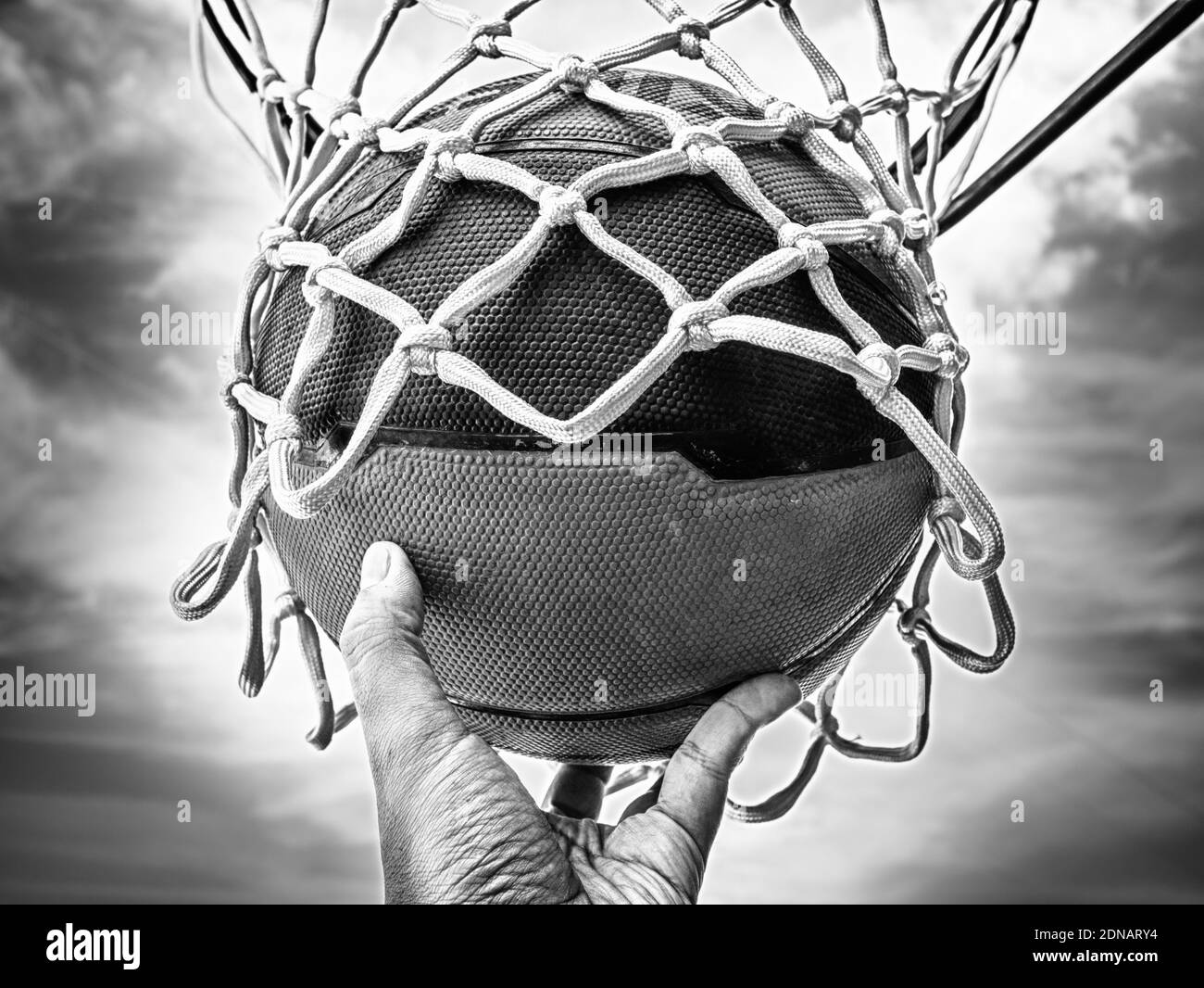 Pelota de sujeción de mano recortada en aro de baloncesto Foto de stock