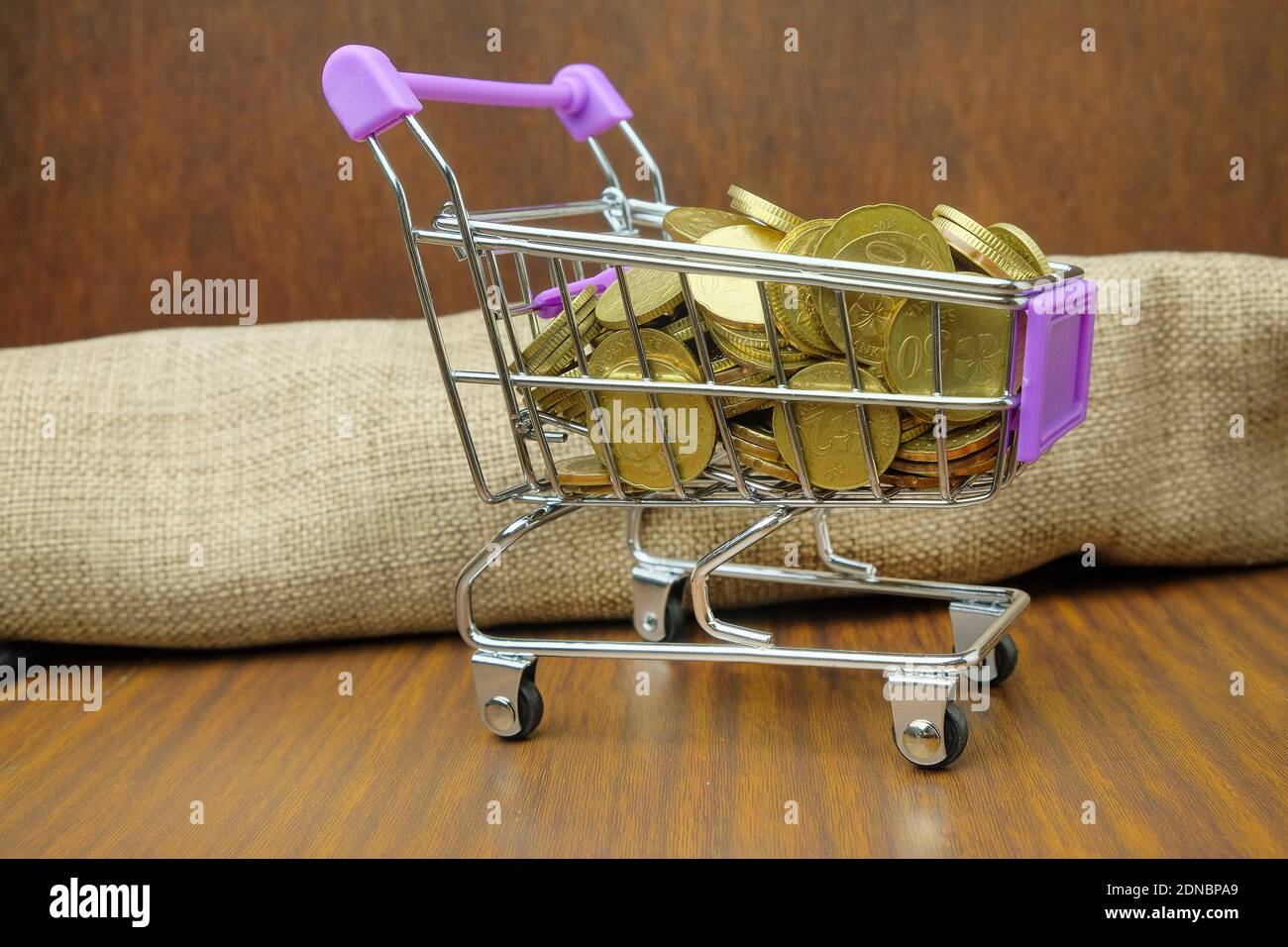 Primer plano de monedas en el carrito de la compra en la mesa de madera Foto de stock