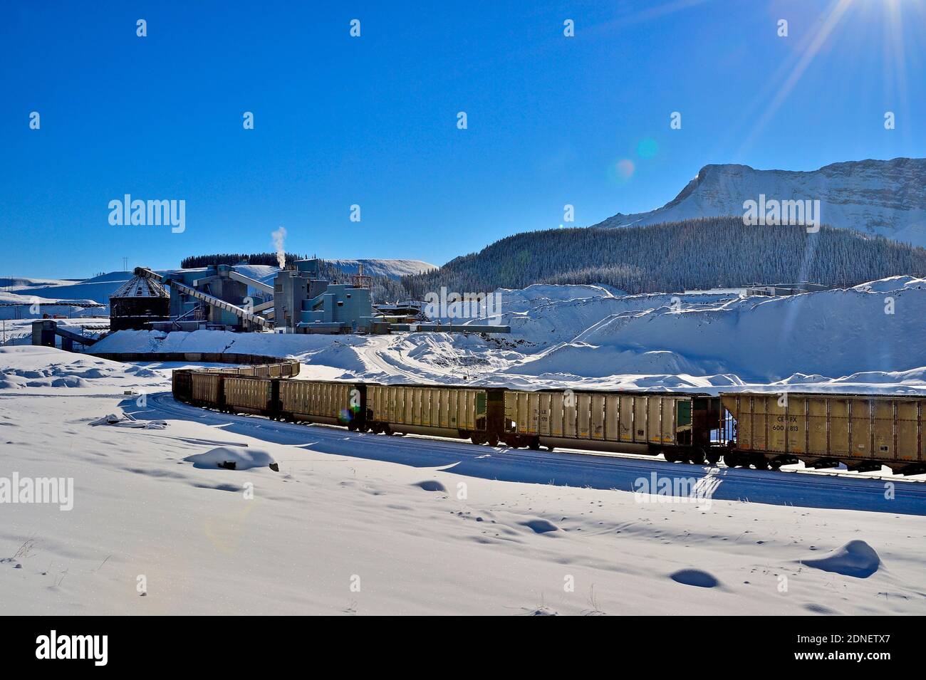 Un paisaje invernal de un ferrocarril nacional canadiense de carga mineral de carbón de una planta de procesamiento de carbón en las estribaciones de las montañas rocosas Foto de stock