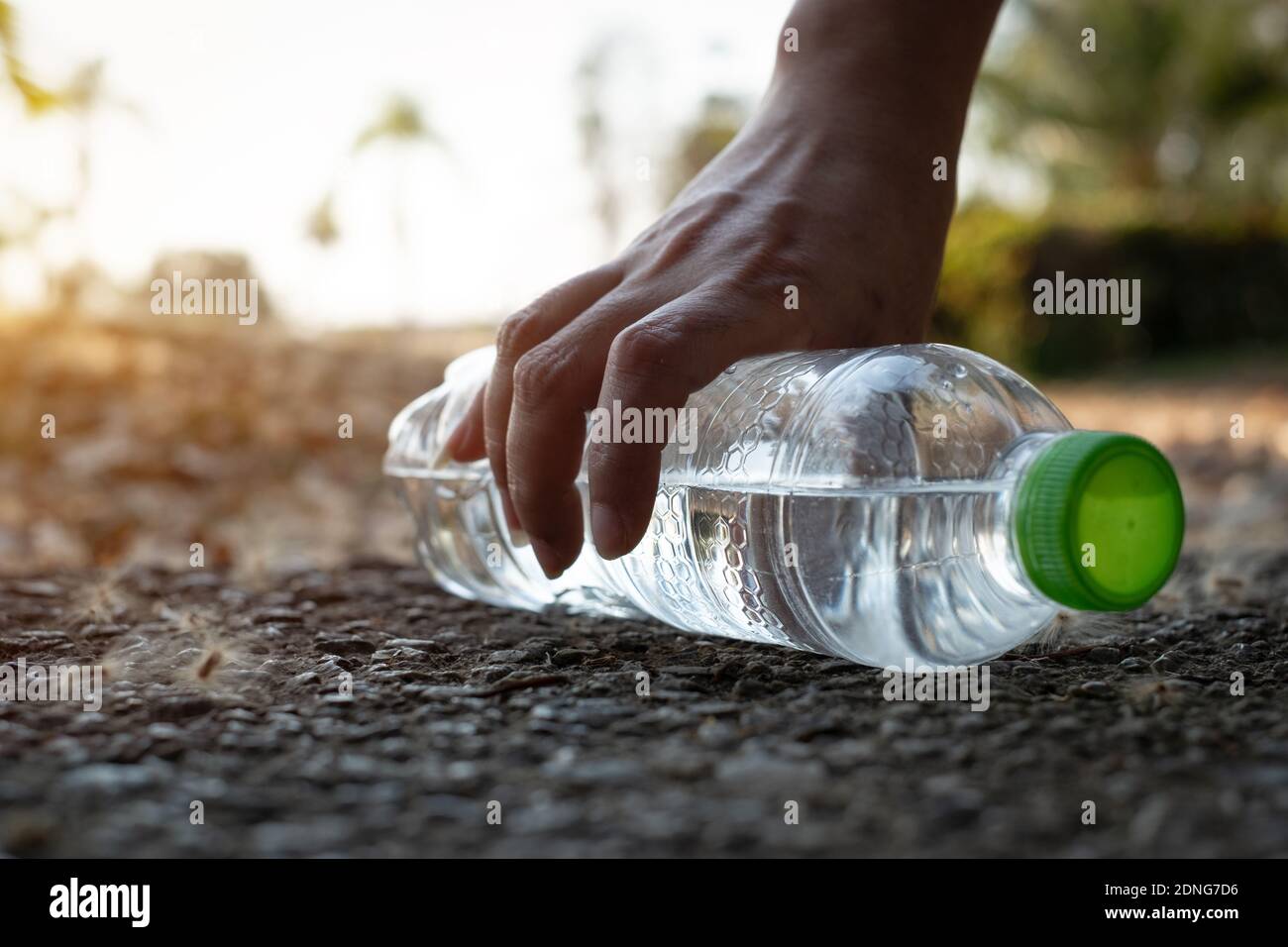 Close Up Hand Picking Up Botella de plástico transparente Bebida de agua  con una gorra verde en el camino en el parque Fotografía de stock - Alamy