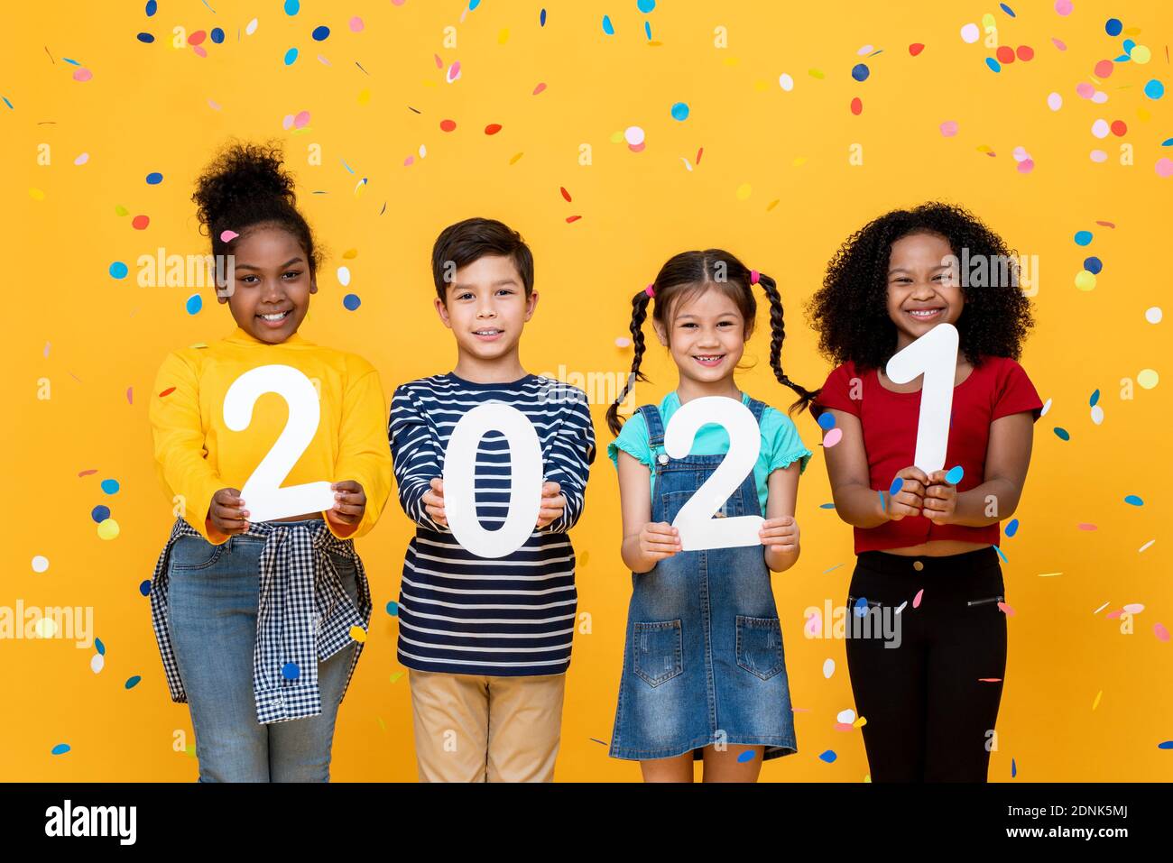 Lindo sonriente carrera mixta niños mostrando números 2021 celebrando nuevo año aislado sobre fondo amarillo Foto de stock