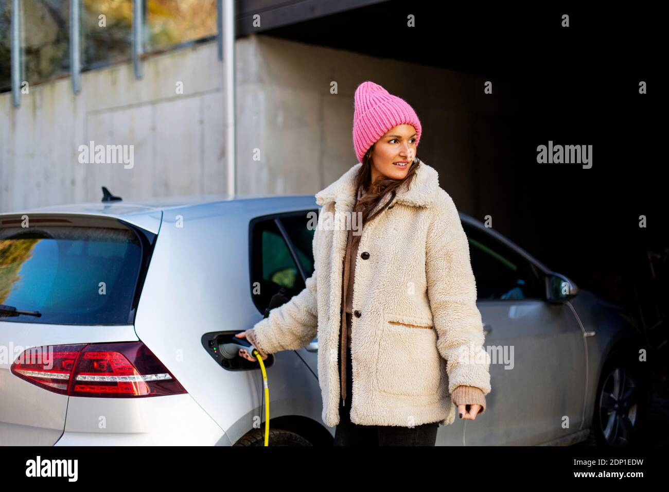 Mujer cargando coche eléctrico Foto de stock