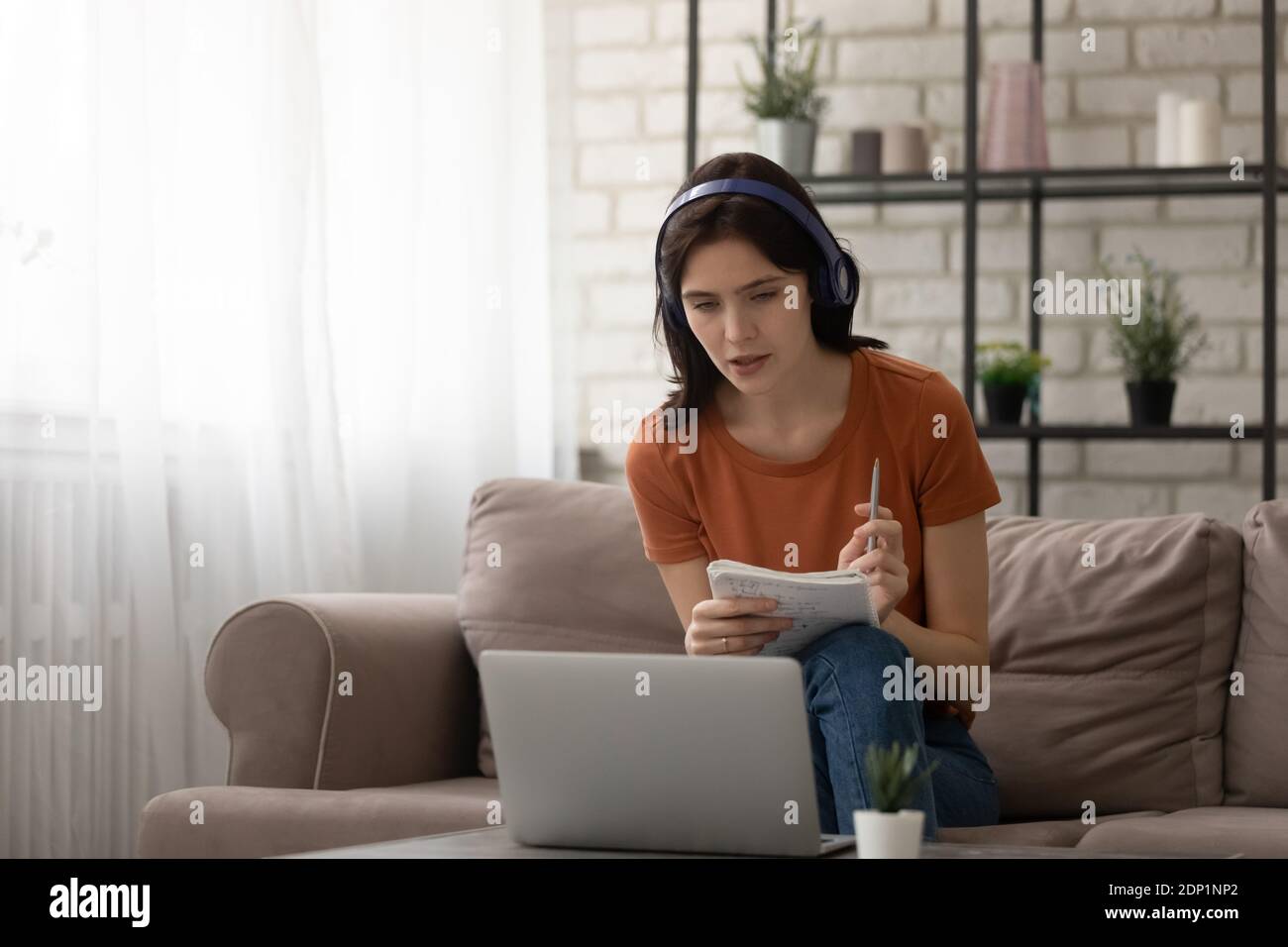 Una mujer joven atenta estudia desde casa en línea durante el período de cuarentena Foto de stock
