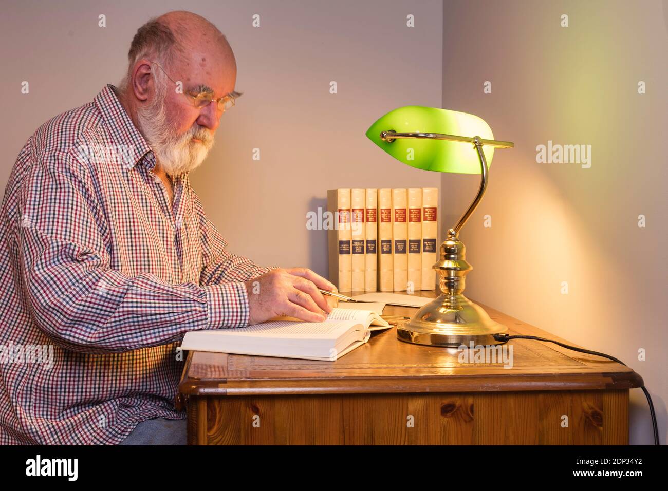 Hombre mayor investigando por la luz de una lámpara de escritorio verde.  Céntrese en la lámpara y la mano de la escritura Fotografía de stock - Alamy
