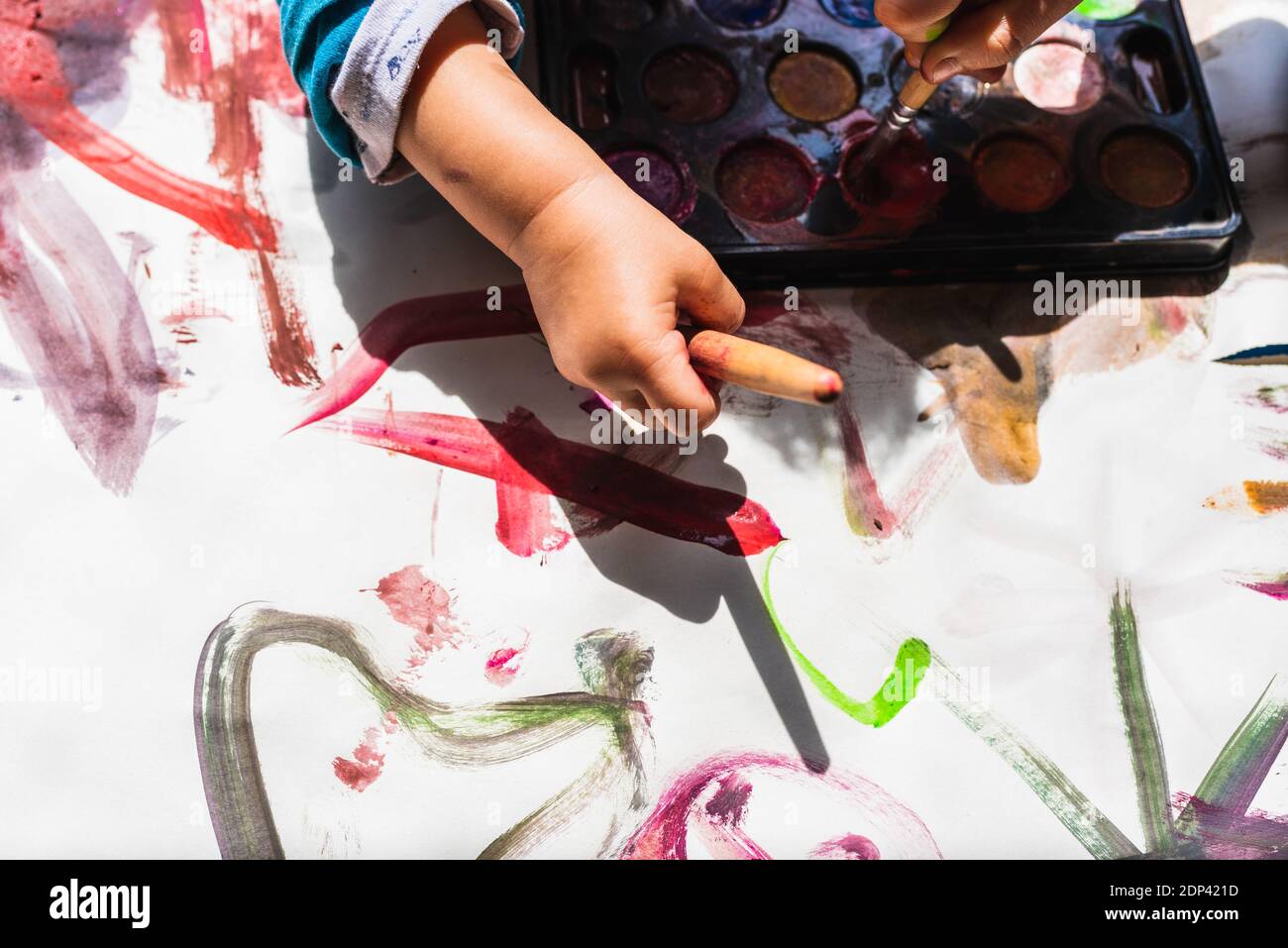 La niña creativa pinta en el suelo con la pintura de los niños un dibujo abstracto de los bebés sin formas. Foto de stock