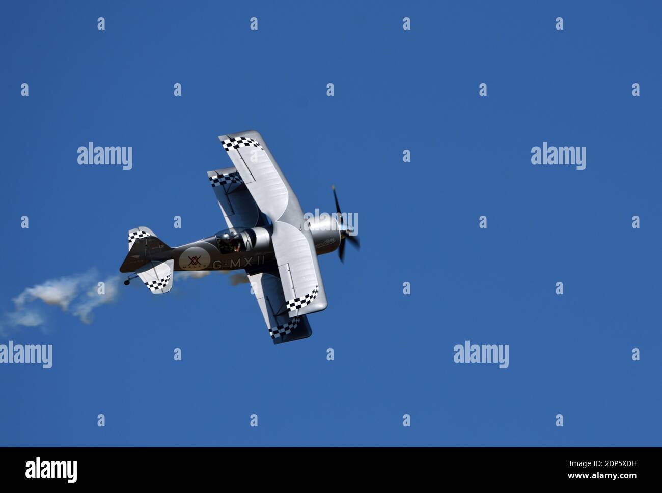 Pitts Modelo 12 stunt biplano con rastro de humo y cielo azul. Foto de stock