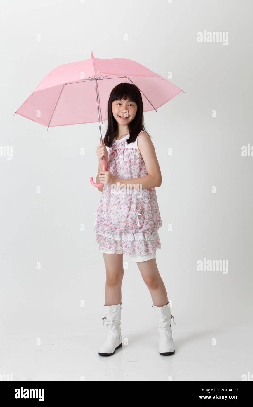 Retrato de una niña adolescente ordeñando paraguas contra blanco Fotografía de stock - Alamy