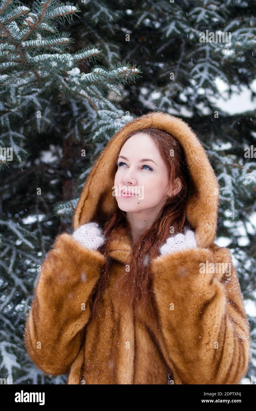 animación nuez Transistor Retrato de joven mujer hermosa con pelo rojo en abrigo de piel sintética en  el fondo del parque de invierno de nieve Fotografía de stock - Alamy