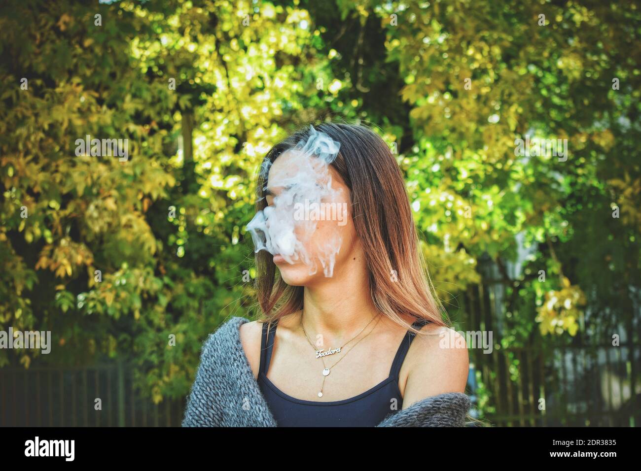 Adolescente Fumando Cigarrillo contra los árboles Foto de stock