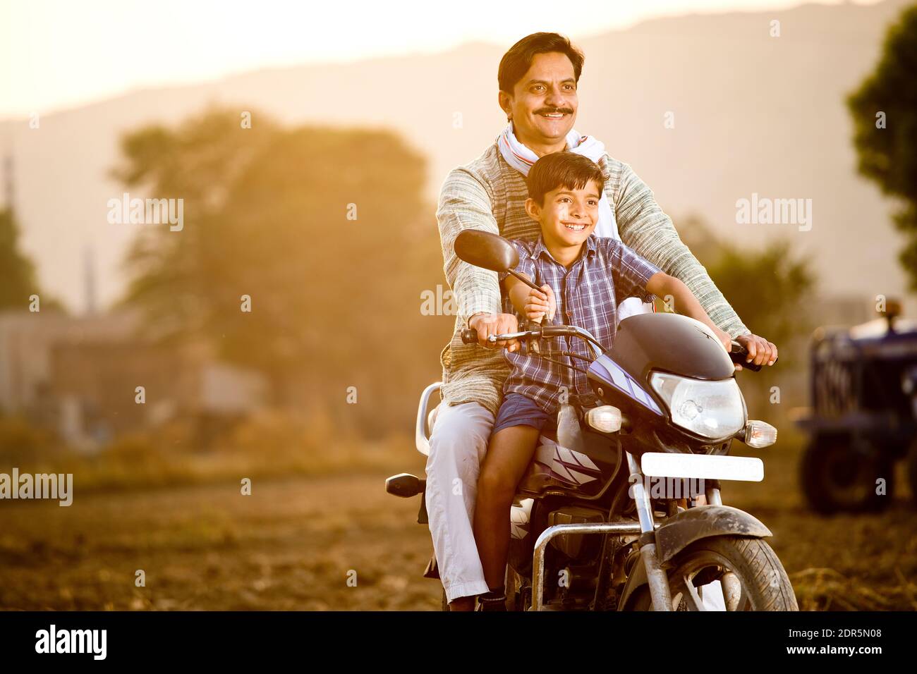 Feliz campesino indio con hijo montando en motocicleta Foto de stock