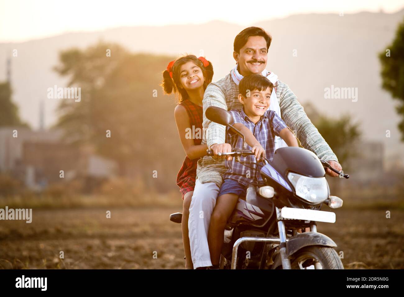 Feliz campesino indio con niños en motocicleta Foto de stock