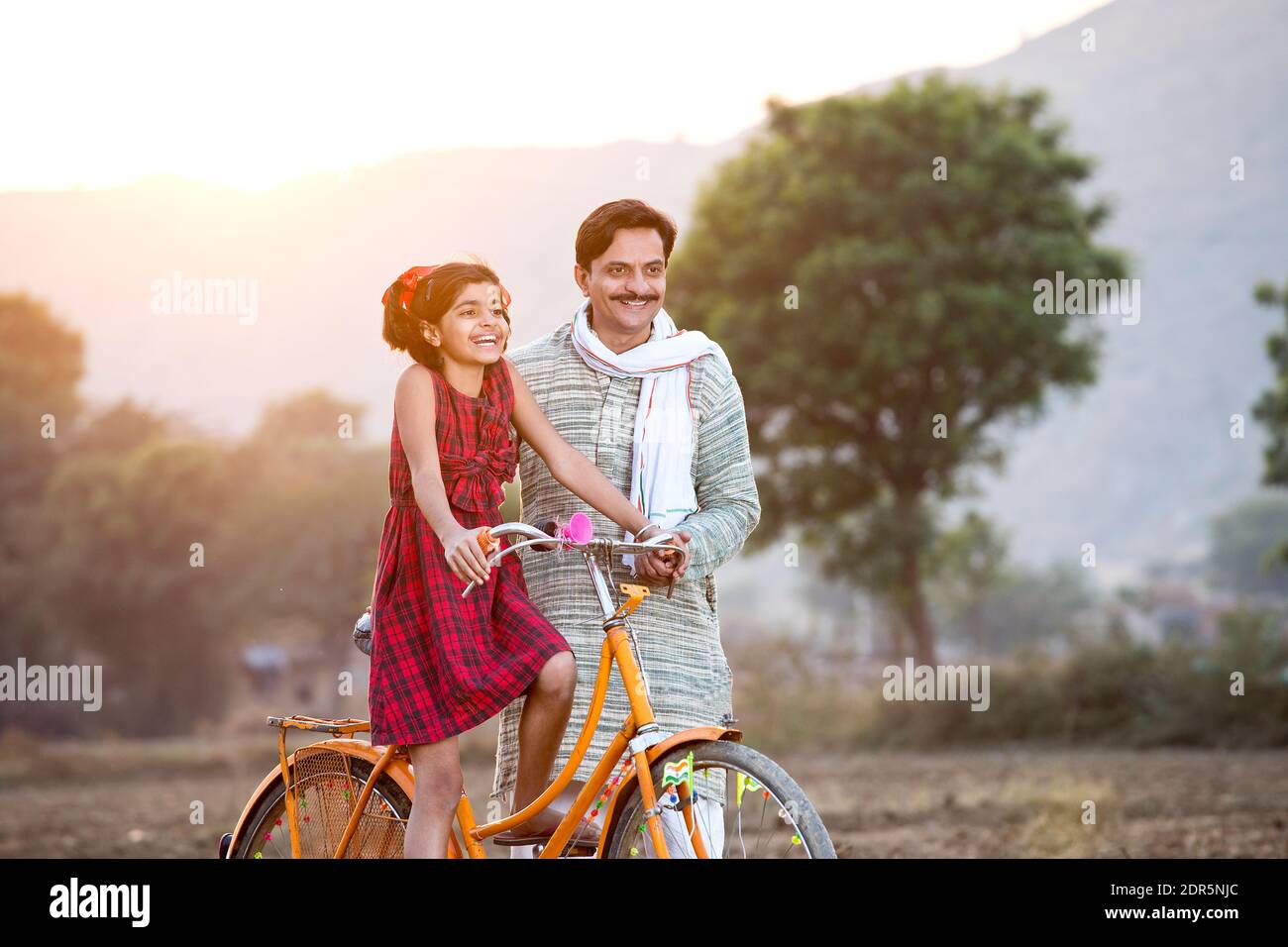 Feliz campesino indio con su hija montando en bicicleta Foto de stock