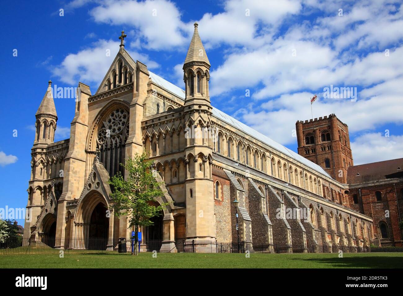 St Albans Cathedral en Hertfordshire Inglaterra Reino Unido con un azul Cielo y algunos nubosidad que es una estructura normanda que data de atrás A los tiempos anglosajones y es el Foto de stock