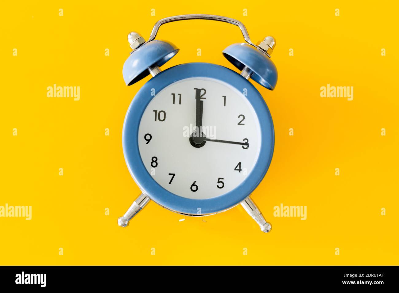 Elegante despertador con cinco a doce en un amarillo antecedentes Foto de stock