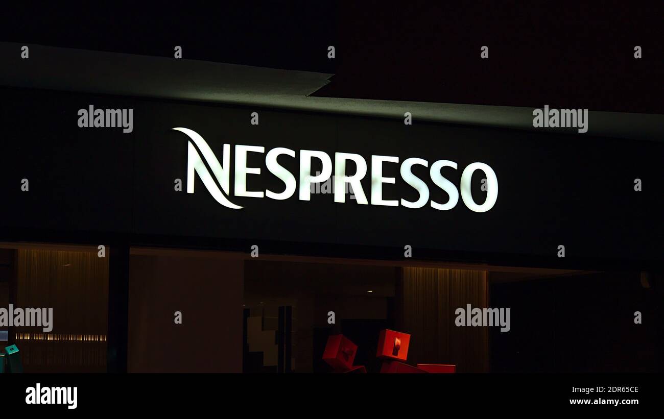 Color blanco iluminado Nespresso (cápsulas de café) logotipo sobre la  tienda de venta al por menor en el mercado en el centro de la ciudad por la  noche Fotografía de stock -