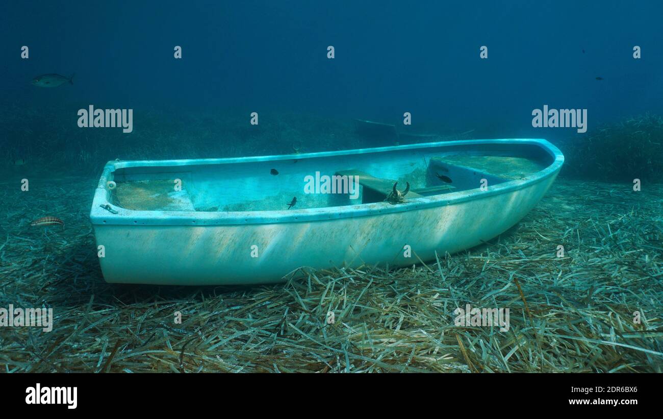 Pequeño barco hundido bajo el agua en el fondo del mar con hojas de algas marinas, mar Mediterráneo, España Foto de stock