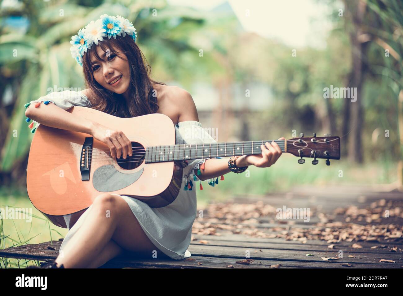 Retrato de una mujer sonriente tocando la guitarra mientras está sentado en  el paseo marítimo en el parque Fotografía de stock - Alamy