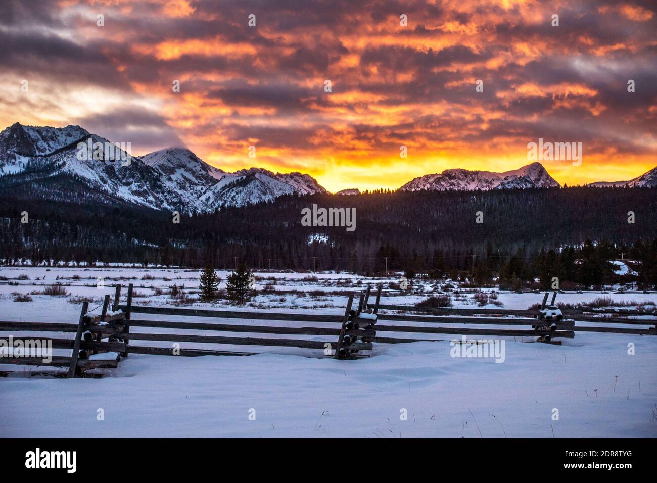 Puesta de sol de invierno con cerca de tren en primer plano y Sawtooth Mts en el fondo Foto de stock