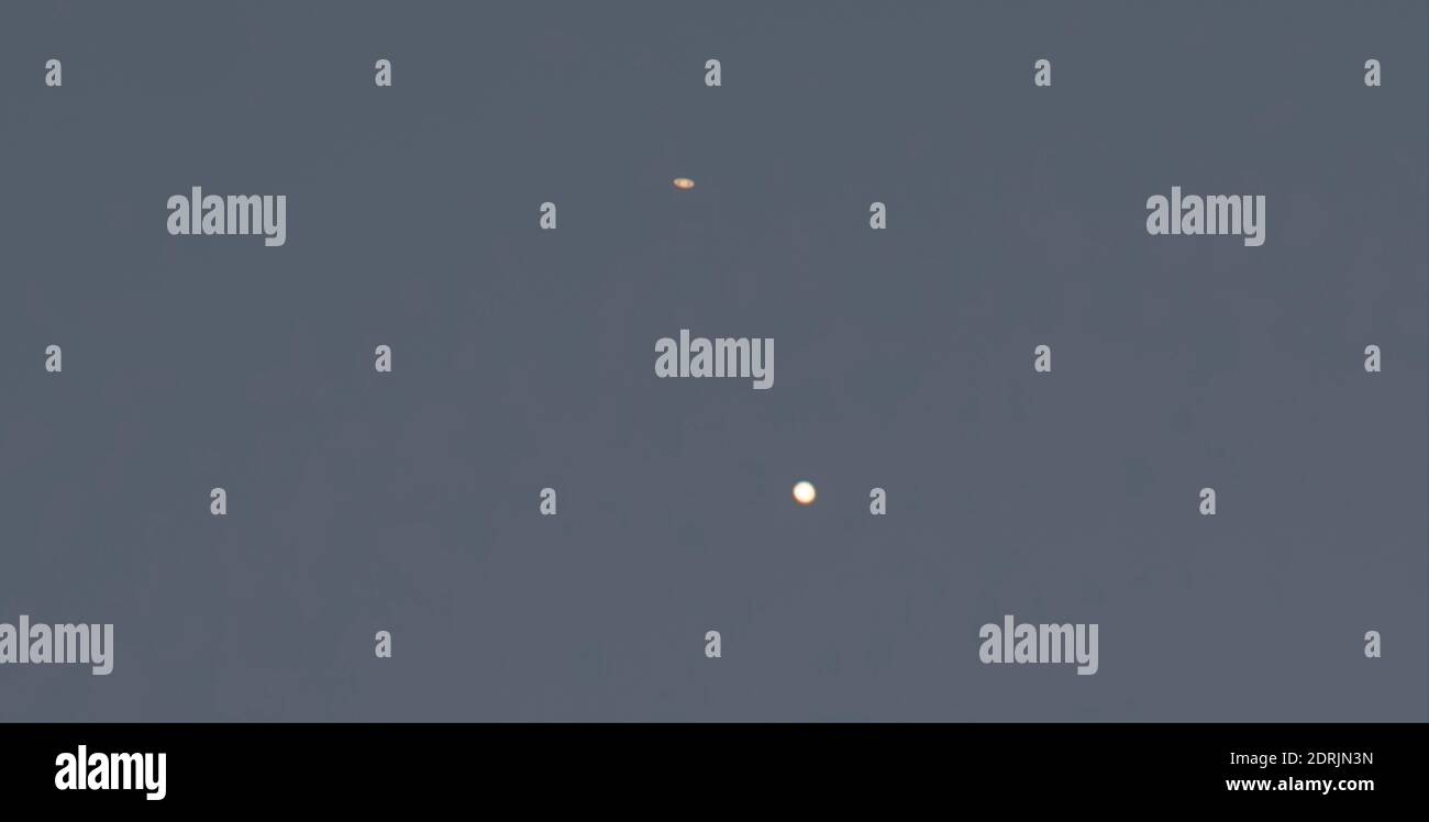Londres, Reino Unido. 20 de diciembre de 2020. El planeta ringed Saturno (arriba a la izquierda) y el planeta gigante Júpiter, con 3 de sus lunas visibles, aparecen después de la puesta de sol sobre los tejados en el cielo del suroeste mientras se acercan a la gran conjunción en la noche del 21 de diciembre - el solsticio de diciembre. La anterior conjunción similar de los dos planetas en esta distancia visible desde la Tierra fue hace 800 años. Ambos planetas están, sin embargo, aproximadamente 400 millones de millas de separación entre sí. Crédito: Malcolm Park/Alamy Foto de stock