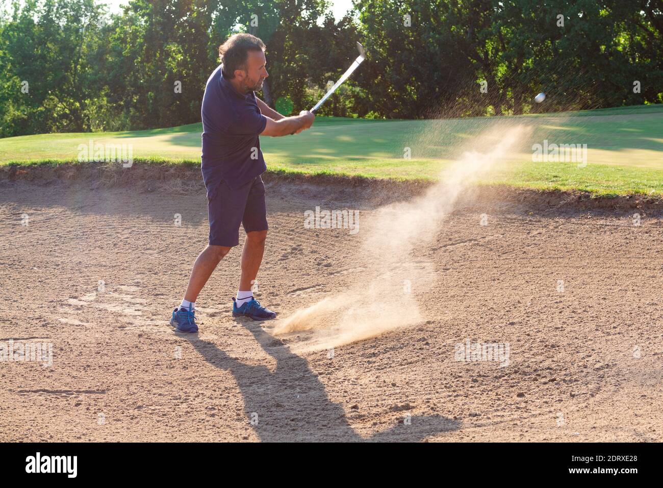 Hombre Golfista Toma un Disparo en el Bunker - Juega Golf en el Bunker Foto de stock