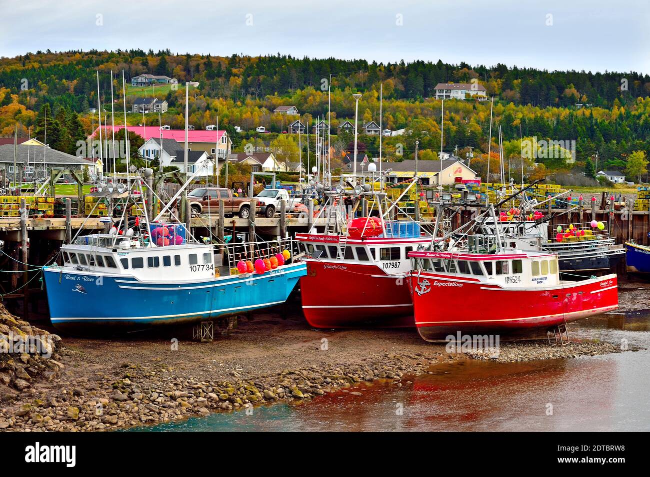 Una imagen horizontal de los coloridos barcos de pesca de la costa este atados al muelle en Alma New Brunswick con la marea baja. Foto de stock