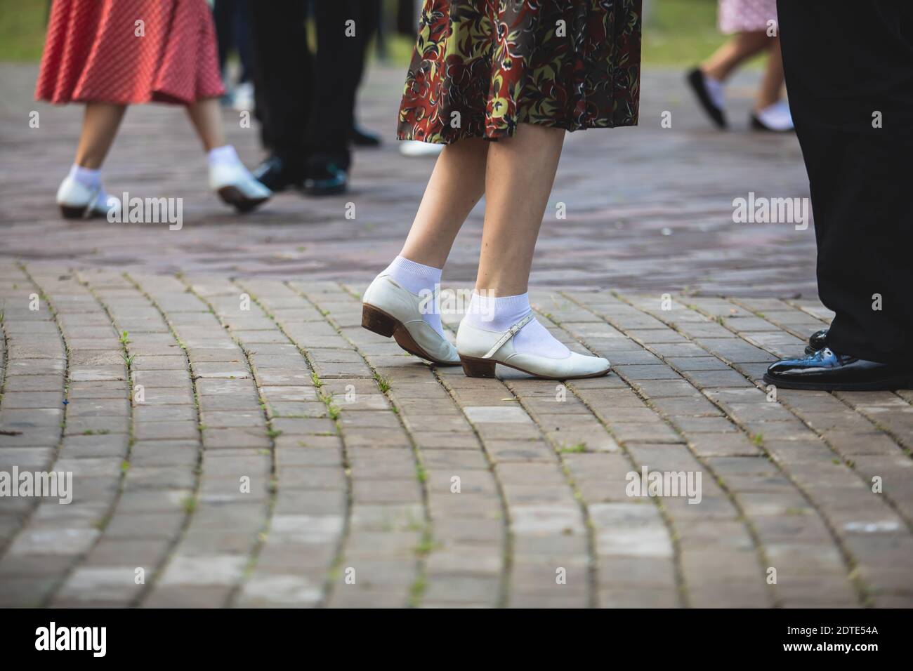 Mujeres jóvenes con vestidos de punto polka vintage bailando en el parque  de la ciudad, vista de cerca de los mismos zapatos de baile negro y  calcetines blancos, swing femenino de jazz
